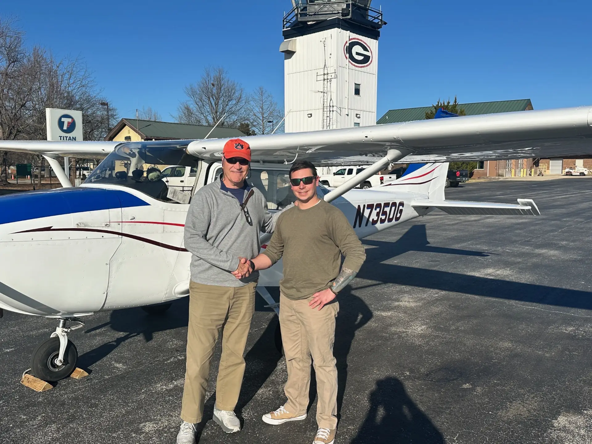 Two man shaking hands in front of a Cessna 172 airplane